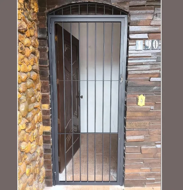 Porta de segurança com grade em arco na entrada de uma casa
